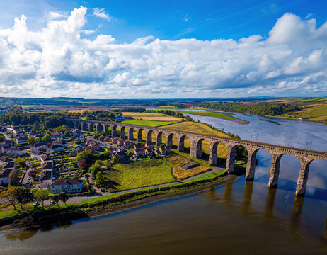 Aerial view of the scenic royal border bridge spanning a river with lush countryside and fields, Berwick-upon-Tweed, United Kingdom.