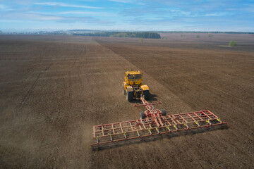 Pre-sowing tillage. Tractor with trailed combined machine working in the field. Drone footage.