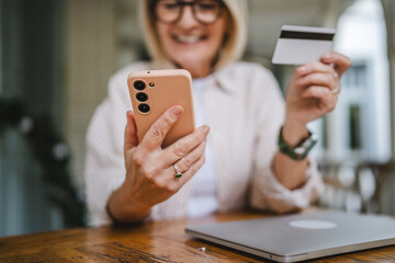 close up of mature woman hands and shop online with credit card