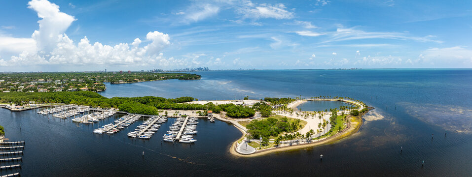 Aerial view of Matheson Hammocks Park with marina, boats, and skyline surrounded by tropical greenery and blue sky, Miami, USA.