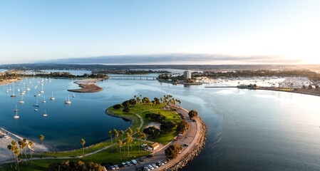 Aerial view of tranquil Mission Bay with sailboats and palm trees under a blue sky, San Diego, USA.