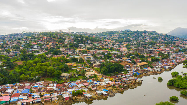 Aerial view of lush houses and trees along a river with hills in the background, Freetown, Sierra Leone.