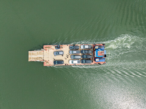 Aerial view of cars on a ferry crossing a river with green water, Bonny, Nigeria.
