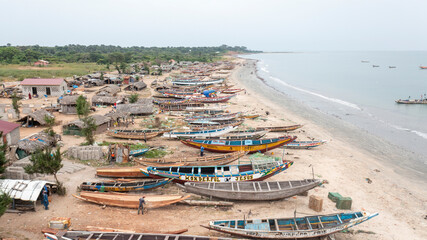 Tujering, The Gambia - 30 October 2021: Aerial view of colorful fishing boats at a traditional fish market by the sandy beach and ocean, Tujering, The Gambia.