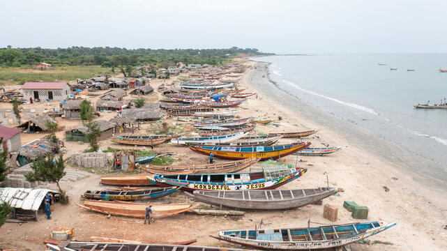 Tujering, The Gambia - 30 October 2021: Aerial view of colorful fishing boats at a traditional fish market by the sandy beach and ocean, Tujering, The Gambia.