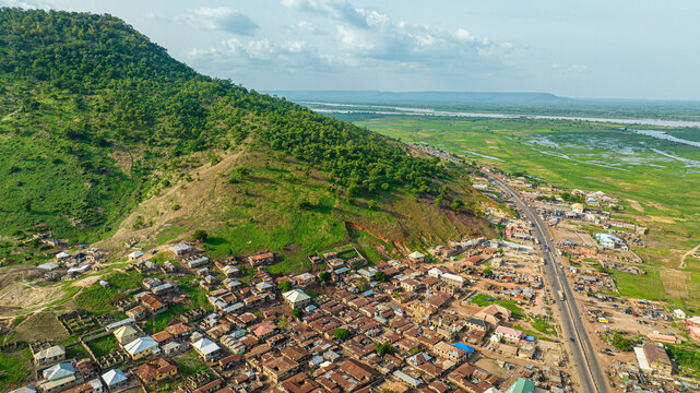 Aerial view of a beautiful village nestled among hills and mountains with greenery and homes, Lokoja, Nigeria.