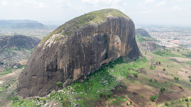 Aerial view of zuma rock surrounded by expansive greenery and a breathtaking valley, Suleja, Nigeria.