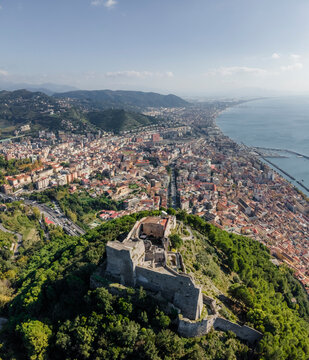 Aerial view of arechi castle overlooking the beautiful coastal city and sea with mountains in the background, salerno, italy.