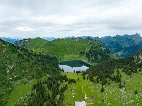 Aerial view of serene Lake Oberstocken surrounded by majestic mountains and lush forest, Erlenbach im Simmental, Switzerland.