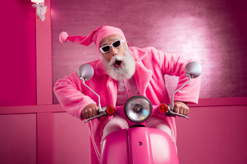 Portrait of eccentric funky man wear pink coat santa hat ride scooter xmas eve hallway background