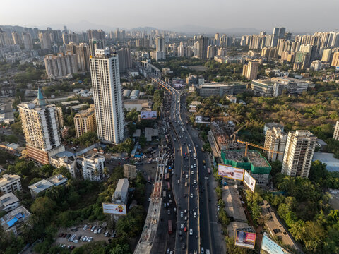 Aerial view of bustling traffic and modern buildings with a bridge and flyover, Thane, India.