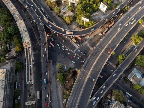 Aerial view of a bustling urban landscape with a busy highway, bridge, and modern buildings, Thane, India.