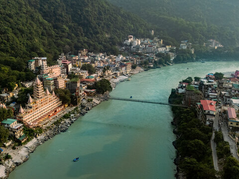 Aerial view of the serene Ganga River with the majestic Laxman Bridge and picturesque mountains, Rishikesh, India.