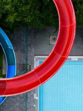 Aerial view of public pools with red and blue waterslides surrounded by greenery, Mariendorf, Germany.