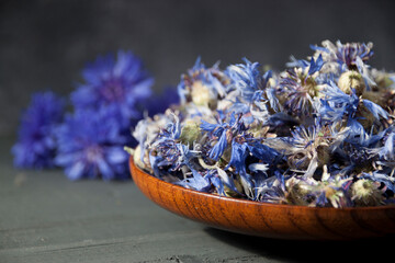 Dry cornflower flowers in a wooden plate on a wooden table