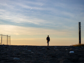 A man in headphones walks along the shore to the sea. A man goes to watch the sunset. A resort place. Solitude.