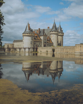 View of chateau de Sully Sur Loire with majestic turrets and serene reflection in the moat, Sully-sur-Loire, France.