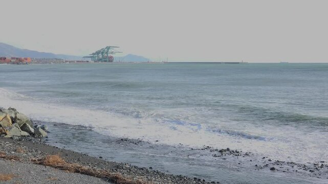 Coastal Port with Waves and Shipping Containers Under Mountains near Genoa Voltri