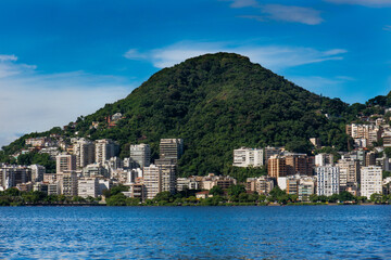 Fototapeta premium LAGOA RODRIGO DE FREITAS NA CIDADE DO RIO DE JANEIRO, MOSTRANDO UMA PARTE DA LAGOA COM UMA MONTANHA E PREDIOS, NUMA TARDE DE SOL COM O CEU AZUL.