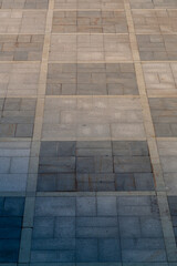 The sidewalk is a pedestrian area paved with slabs in a checkerboard pattern