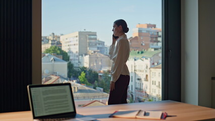 Nervous woman ceo calling phone standing at office window. Frustrated lady