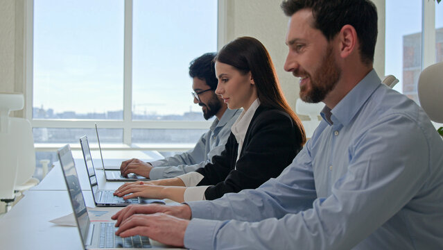 Row of multiracial customer support agents provide service with laptops smiling professional business team programmers businessmen and businesswoman working desktop pc computers at co-working office - Powered by Adobe