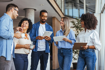 Diverse Team Engaged In Casual Office Discussion With Technology