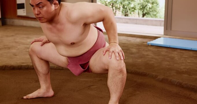 Stretching, sumo and wrestling with Japanese man in arena for training, shiko ritual and tournament. Festival, competition and game with asian person in dohyo ring of temple for culture and sports