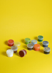 Colorful gouache paints in containers on yellow background