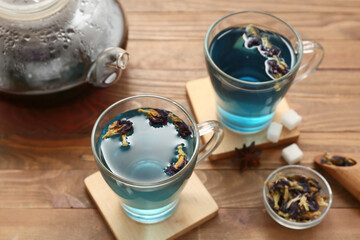 Cups with butterfly pea flower tea on wooden background, closeup