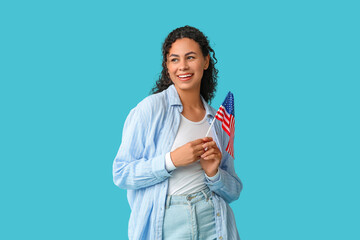 Beautiful young happy African-American woman with USA flag on blue background