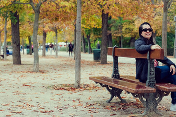 Mujer latian sentada en una banca en un parque en Madrid