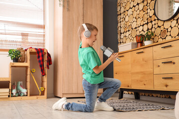 Cute little boy with microphone and headphones singing at home