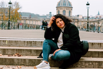 Mujer latina sonriendo sentada por las calles de Paris