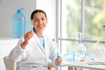 Fototapeta premium Happy female young scientist with test tubes of water samples in research laboratory