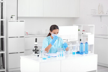 Female young scientist with professional glassware examining water quality in research laboratory