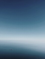 Obraz premium Solitary cargo ship on vast ocean with clear blue sky