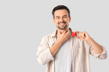Handsome man with thyroid gland model on grey background