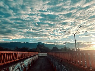 A stunning urban sunrise captured from a pedestrian bridge, showcasing the city's skyline bathed in...