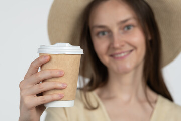 A woman with long hair smiles while holding a coffee cup in a cozy indoor environment. She is...