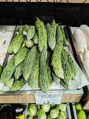 Fresh green bitter gourds on display in grocery store