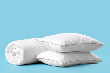 Soft warm blanket and pillows on blue background