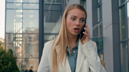 Upset frustrated angry stressed caucasian woman businesswoman walk on street near office talking arguing on mobile phone girl manager lady entrepreneur answer unpleasant business call using smartphone