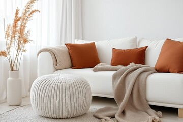 Cozy living room interior with white sofa terra cotta pillows knitted pouf, beige blanket. Scandinavian style home decor. Relaxing, serene atmosphere. Modern comfy furniture. Stylish home design.