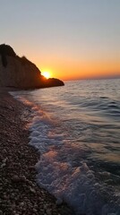 Obraz premium Serene Sunset Over Tranquil Waters, a breathtaking scene showcasing a vibrant sky reflecting warm hues on a quiet sea, gentle waves caressing the sandy beach.