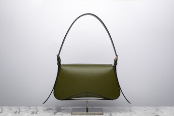Luxury women's bag on a white background. Dark green color, leather expensive bag isolated on the marbel in the studio