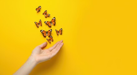 Hand releasing butterflies against vibrant yellow background