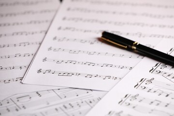 Sheets of musical notes and pen as background, closeup