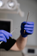Dentist holding dental floss and tools for oral hygiene demonstration in a clinical setting