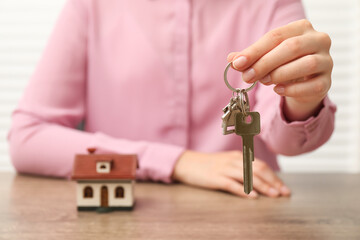 Real estate agent with house key at table, closeup